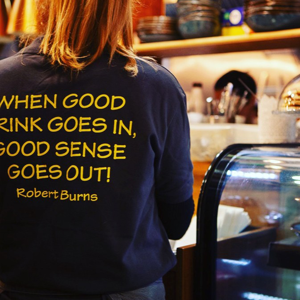 A barista tamping espresso grounds behind the counter
